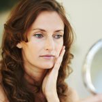 Pretty woman looking herself in mirror at home