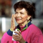 An older woman putting sunscreen on her face